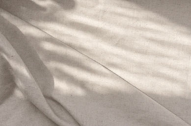  Soft sunlight on neutral linen fabric creating a calm, hopeful atmosphere